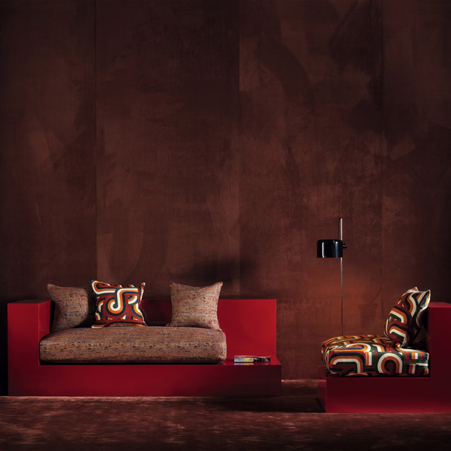 Ember-brown upholstery with bold red, teal, cream and black curling motifs