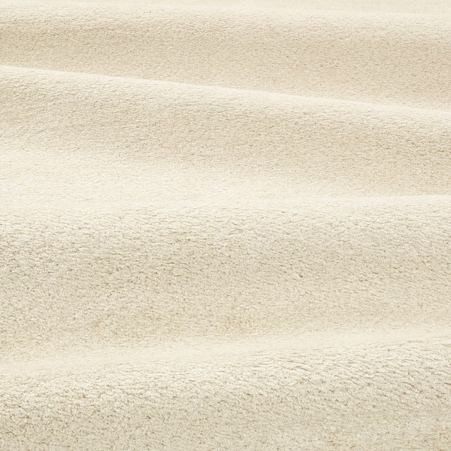 Close-up of pale stone-beige boucle fabric with soft horizontal folds and nubby texture