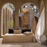 Warm sandy beige woven fabric draped across a bed with a softly frayed edge