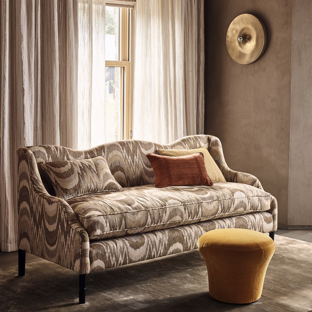 Warm cognac upholstery with large ivory and taupe organic wave motifs on a curved sofa