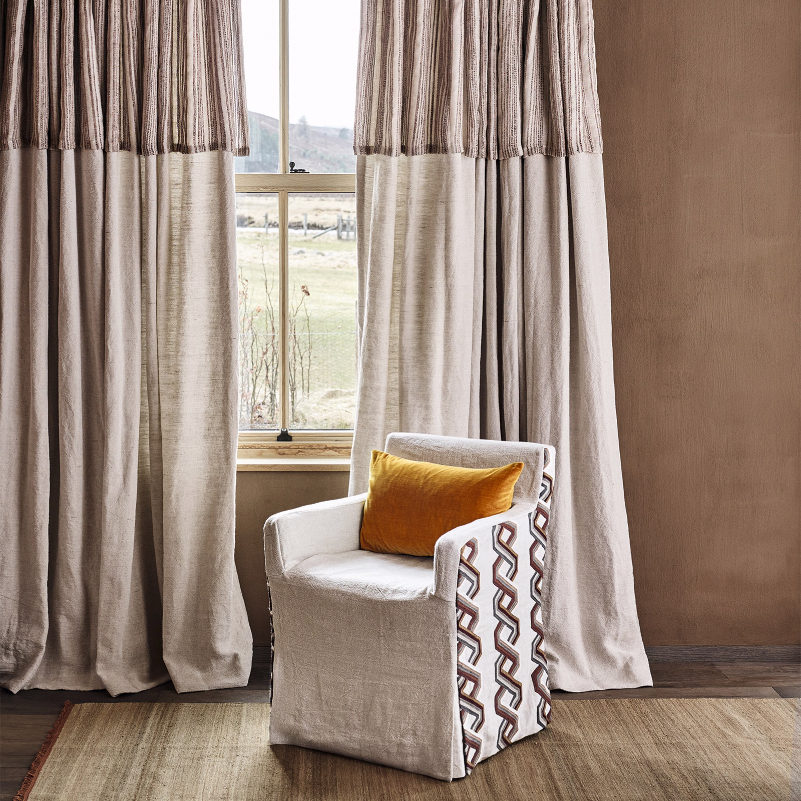 Warm cognac-taupe curtains with slubbed vertical texture and deep fold shading