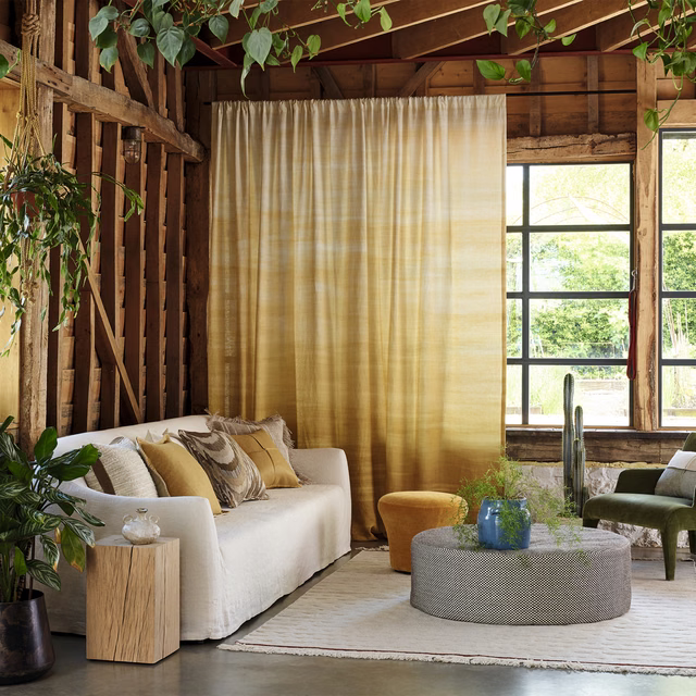 Ochre-gold curtain with softly striated texture glowing beside a sunlit window