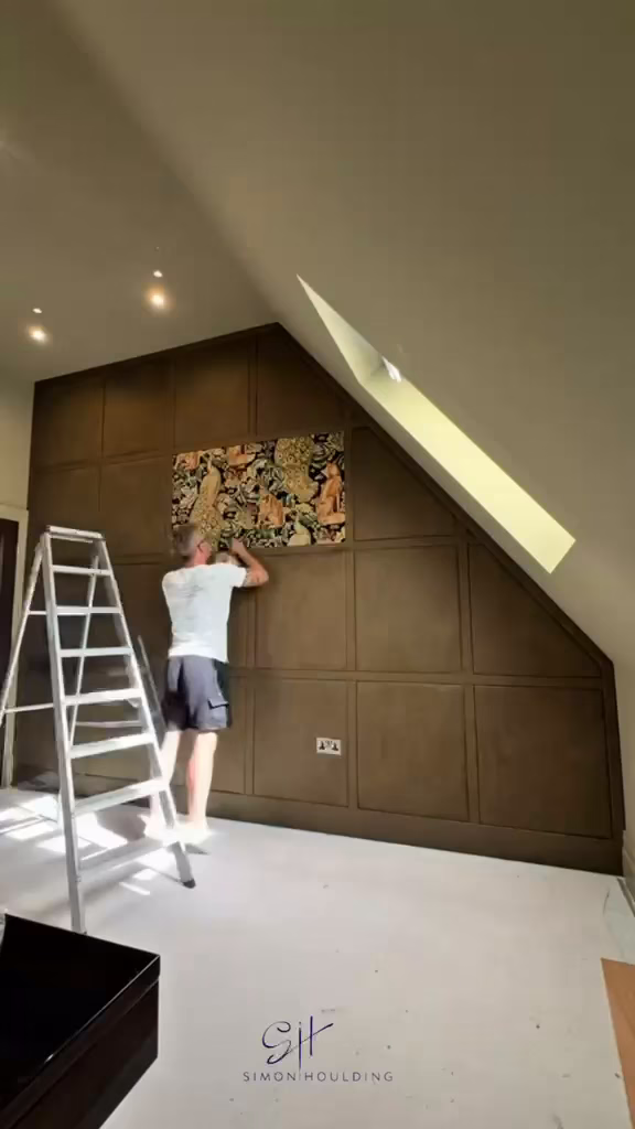 A wall of acoustic fabric panels going up, from bare plaster to a finished grid