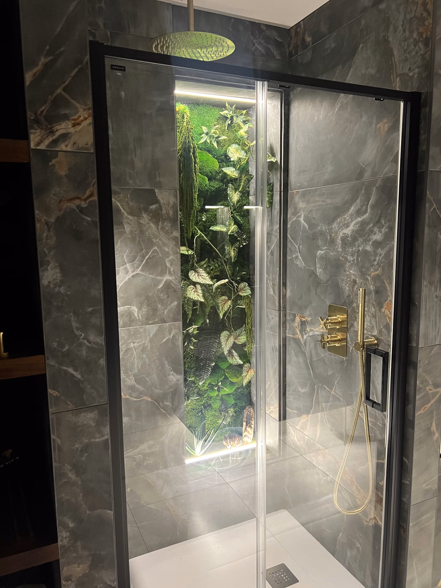 Preserved moss and foliage encased in glass in a shower room