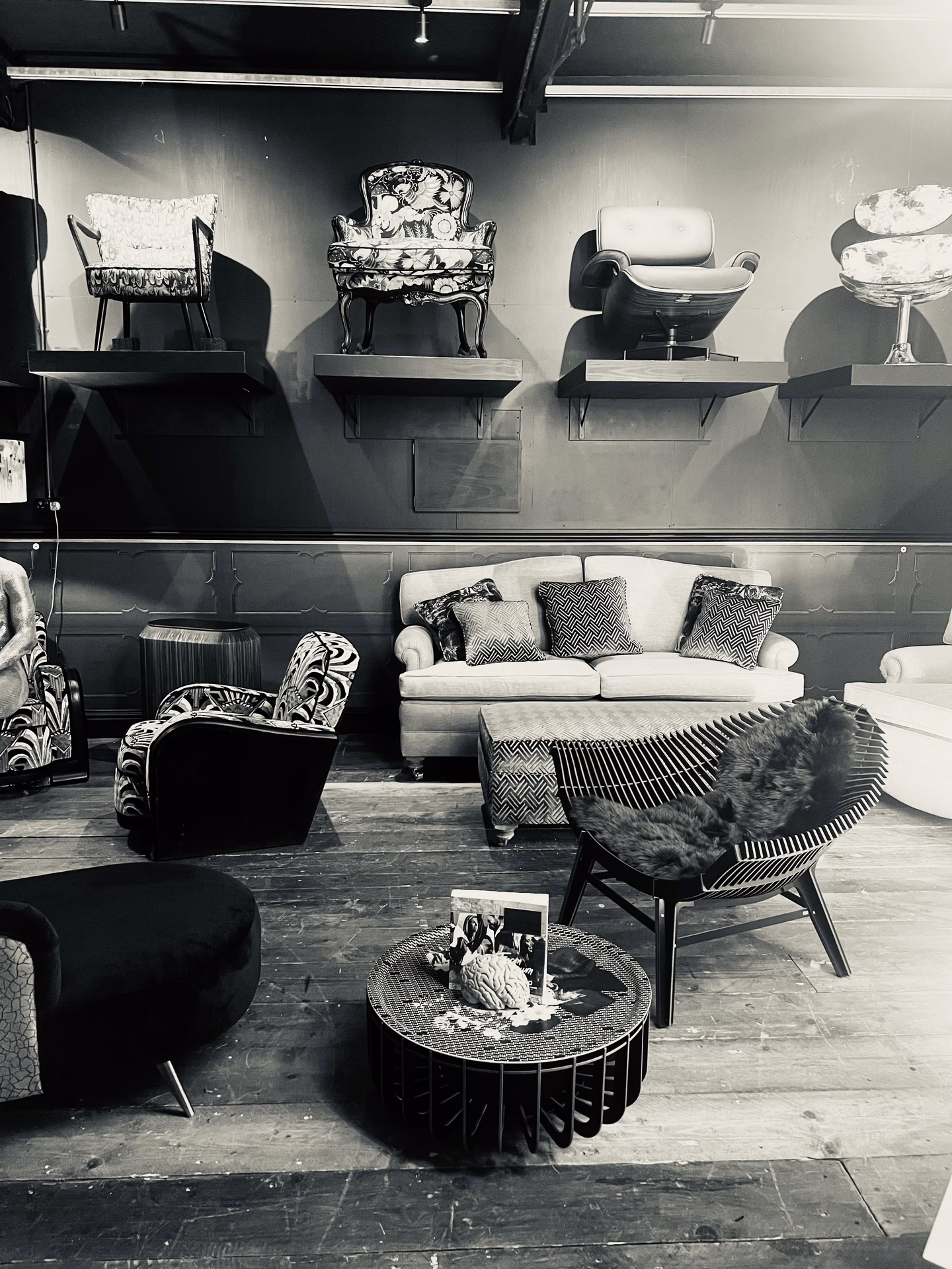 The Simon Houlding showroom in Heybridge: reupholstered chairs displayed on shelves above a cream sofa, a fur-draped hoop chair and a velvet ottoman on a reclaimed timber floor