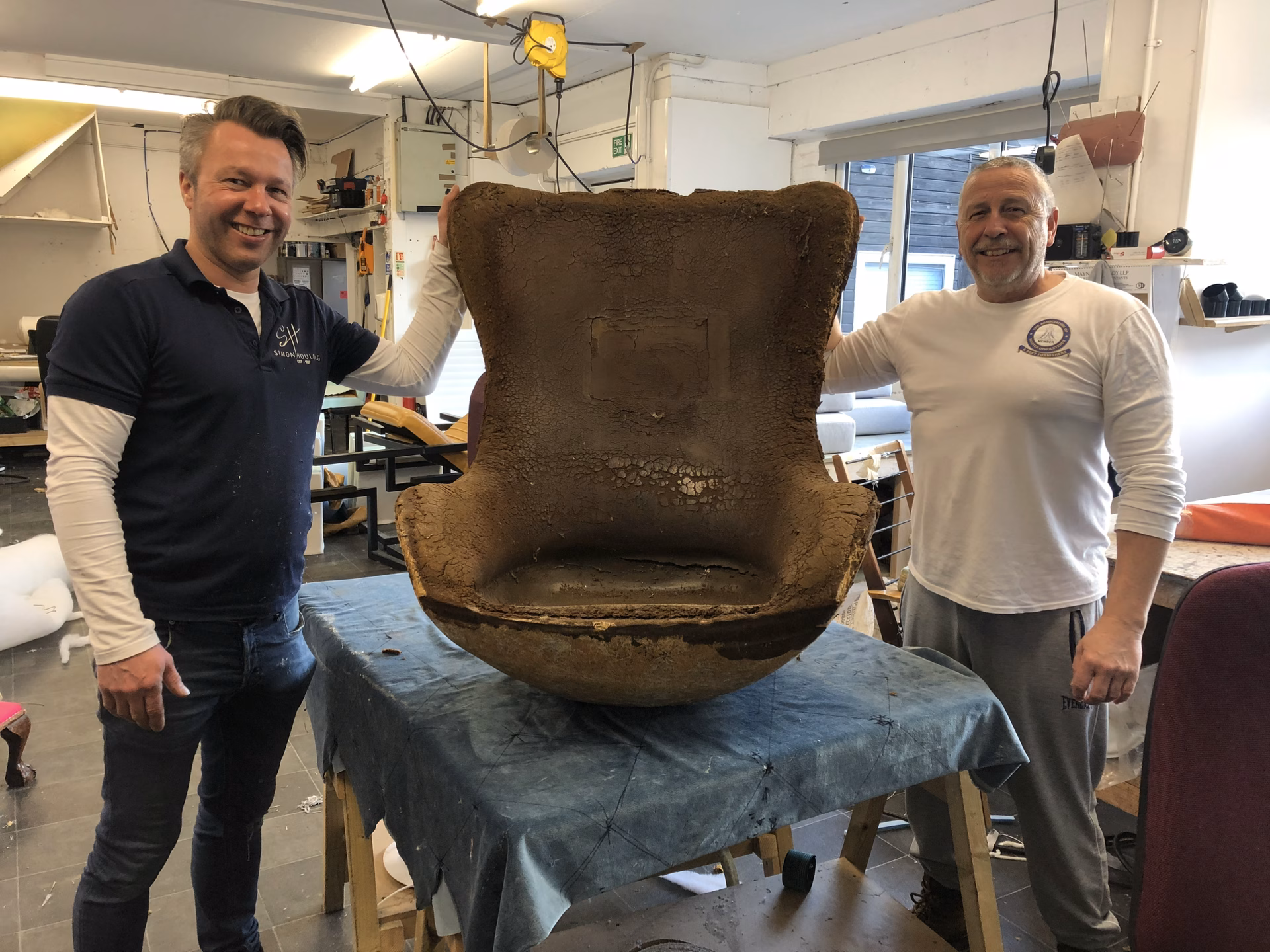 Simon and an upholsterer with the chair stripped back to its shell