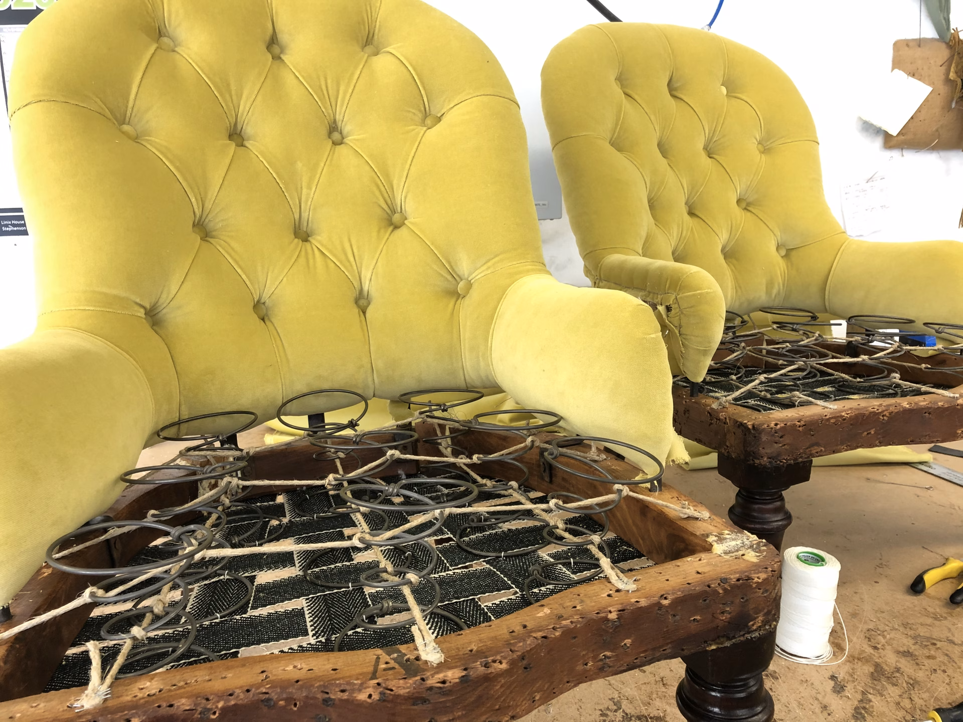 A pair of buttoned chairs with the seats stripped back to the webbing