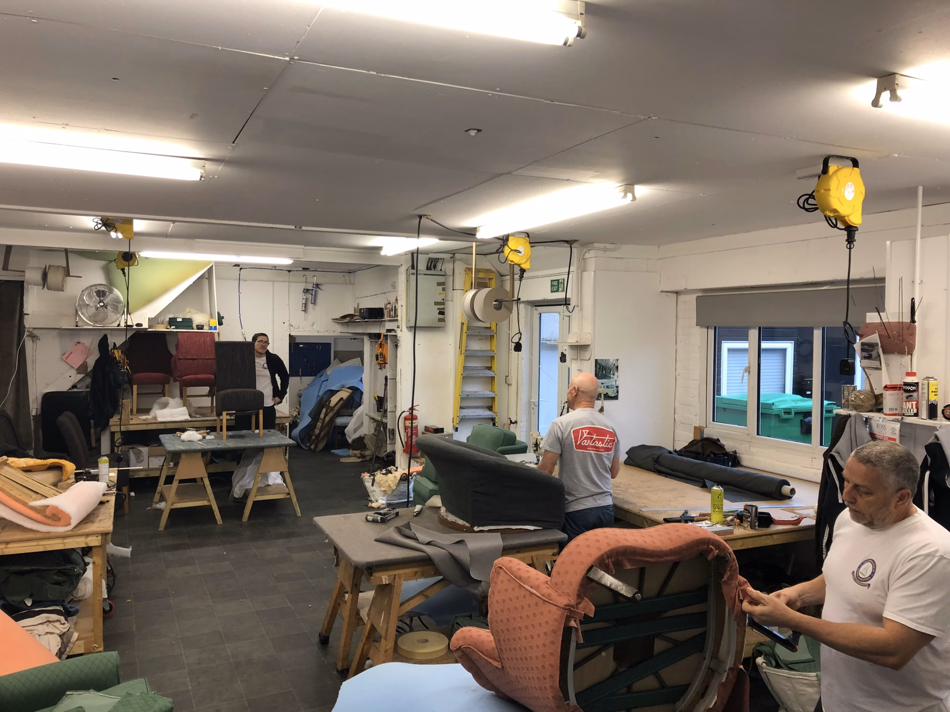 The workshop floor mid-job, four upholsterers at their benches